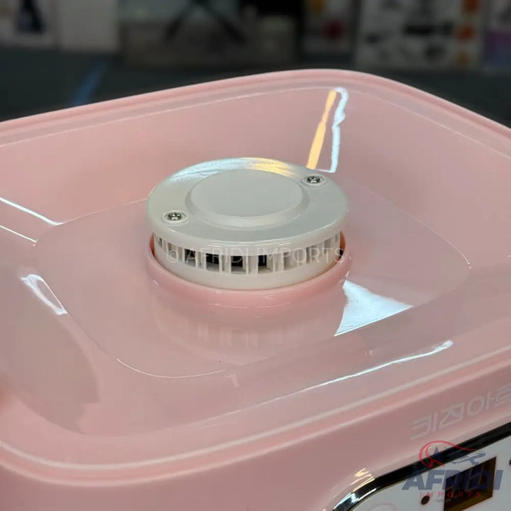 Pink countertop cotton candy machine with a central heating element.