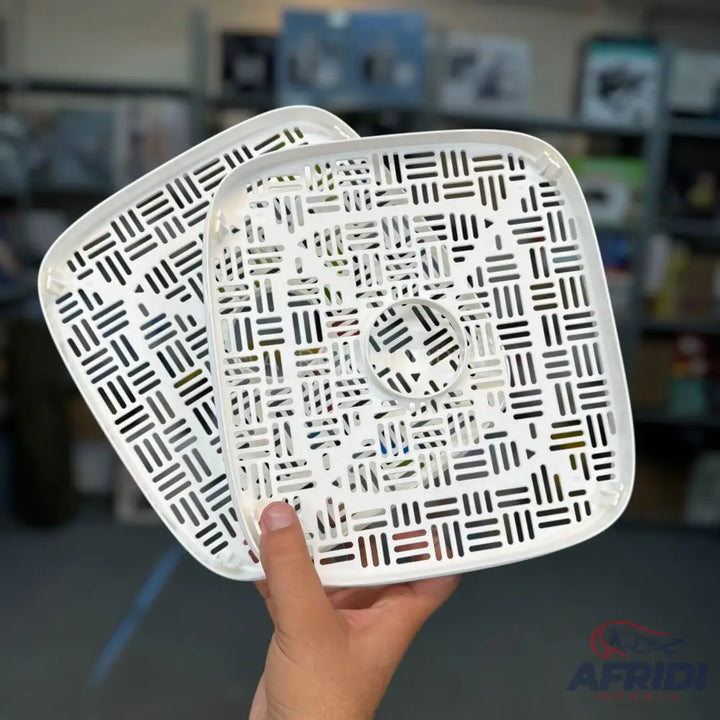 Two white square-shaped plastic mesh trays with a circular opening in the center of one.