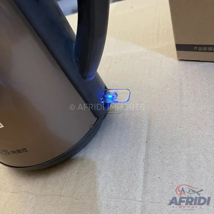 A dark-colored electric kettle with a glowing blue indicator light.