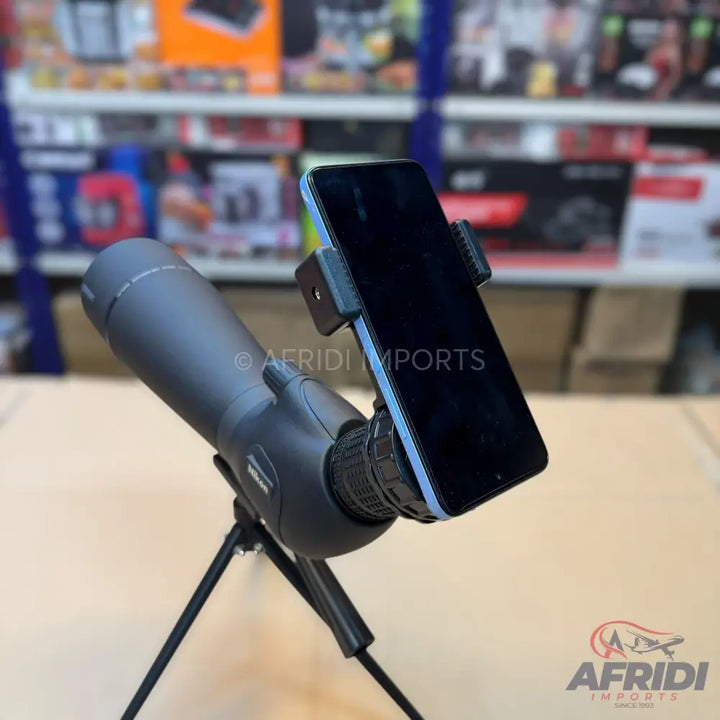 A black spotting scope with an attached smartphone adapter and tripod.