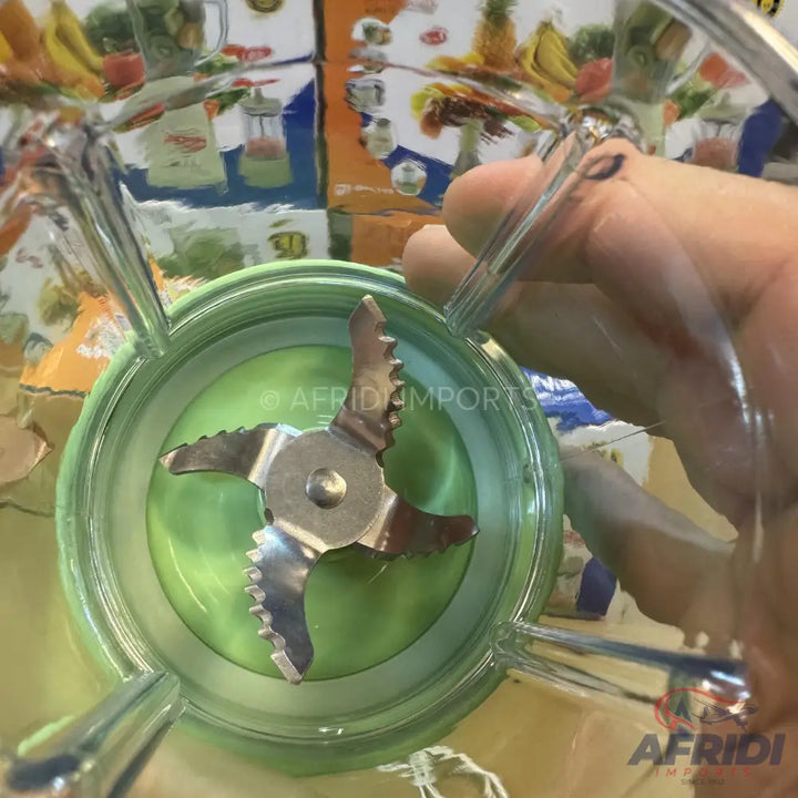 A blender with a four-pronged serrated blade and a green base.