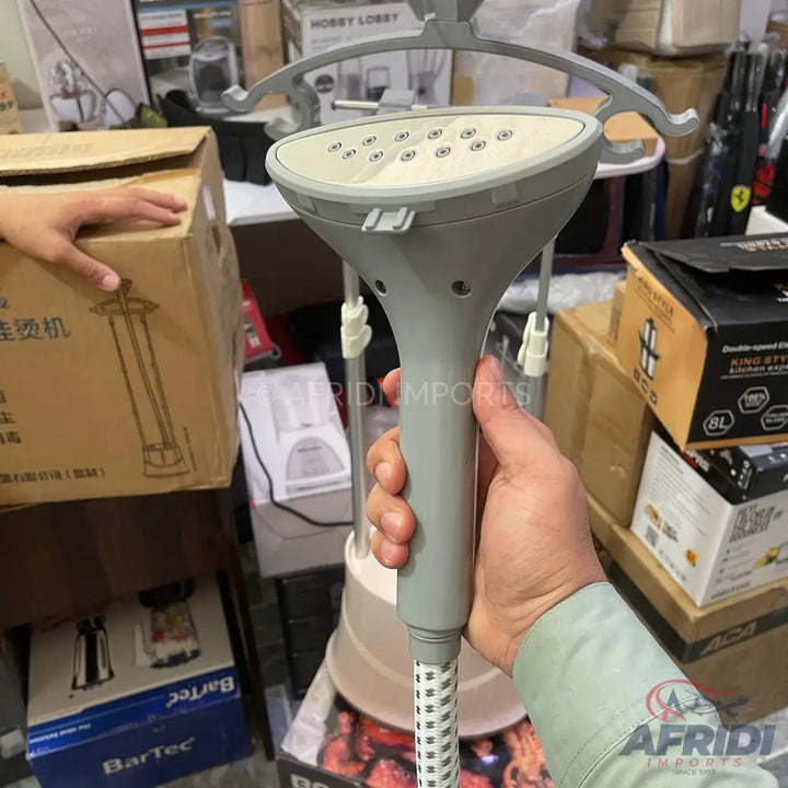 A handheld garment steamer with a grey head and handle, featuring multiple steam holes.
