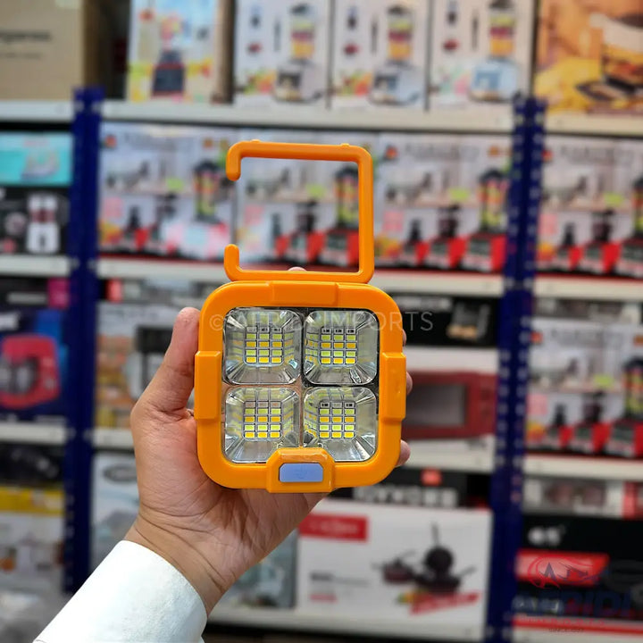 Orange portable LED work light with four square panels and a hook handle.