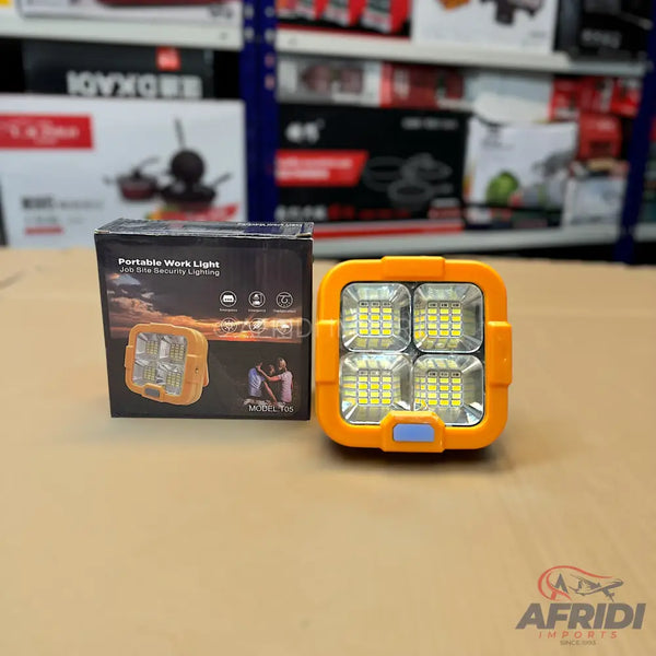 An orange portable work light with four square LED panels and its packaging box.