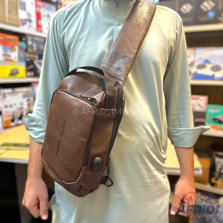 Brown leather sling bag with a USB charging port.