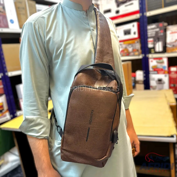 Brown leather anti-theft sling bag with a USB charging port.