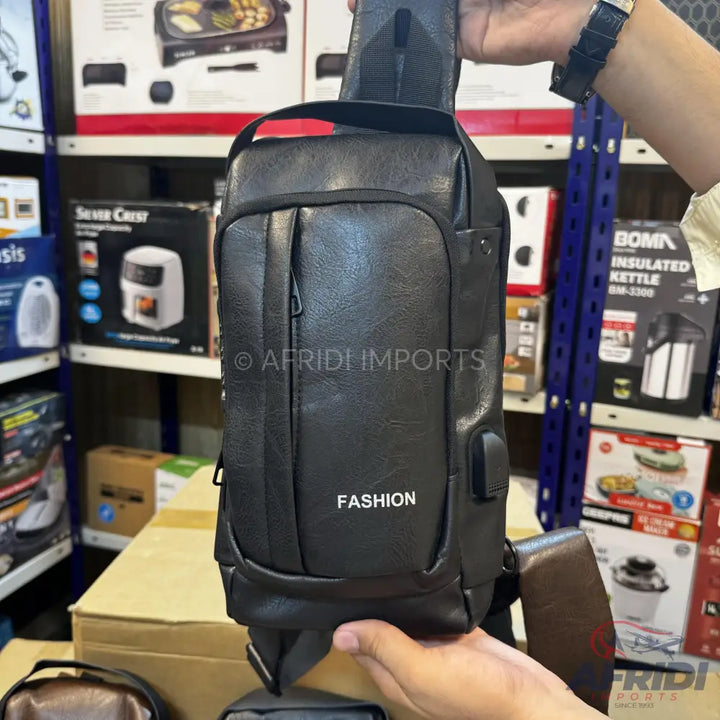 Black faux leather sling bag with a front zip pocket and an external USB port.