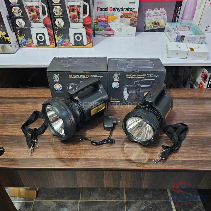 Two black handheld searchlights with chargers and carrying straps.