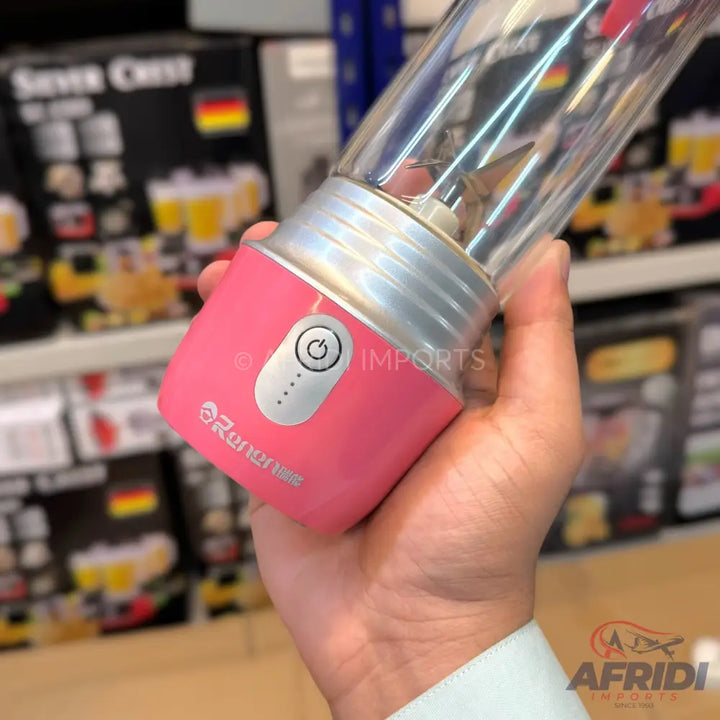 A person holding a pink portable blender with a clear cup and silver accents.