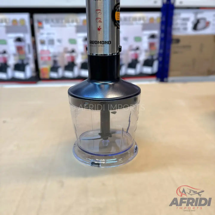 A silver and black immersion blender with a clear plastic chopper attachment.