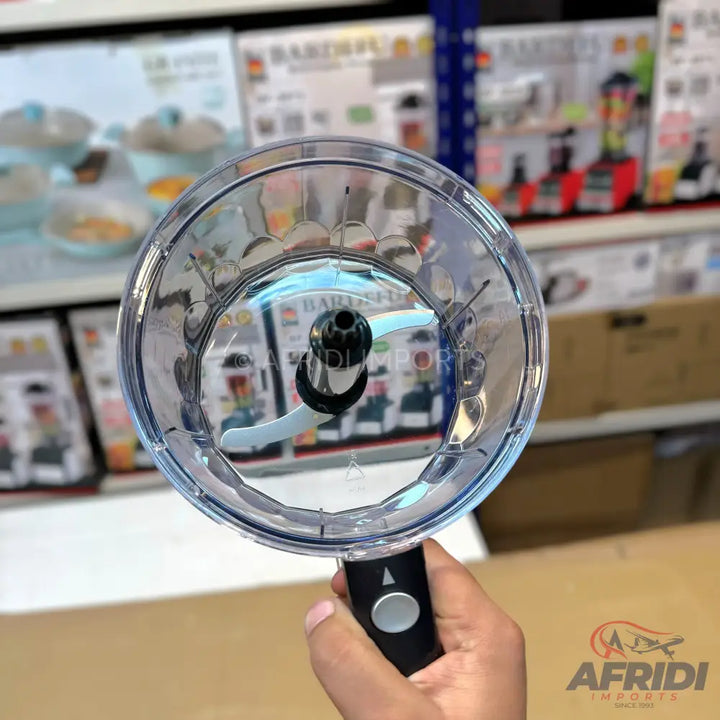 A clear plastic food chopper with a two-blade stainless steel cutting attachment and a black handle with a silver button.