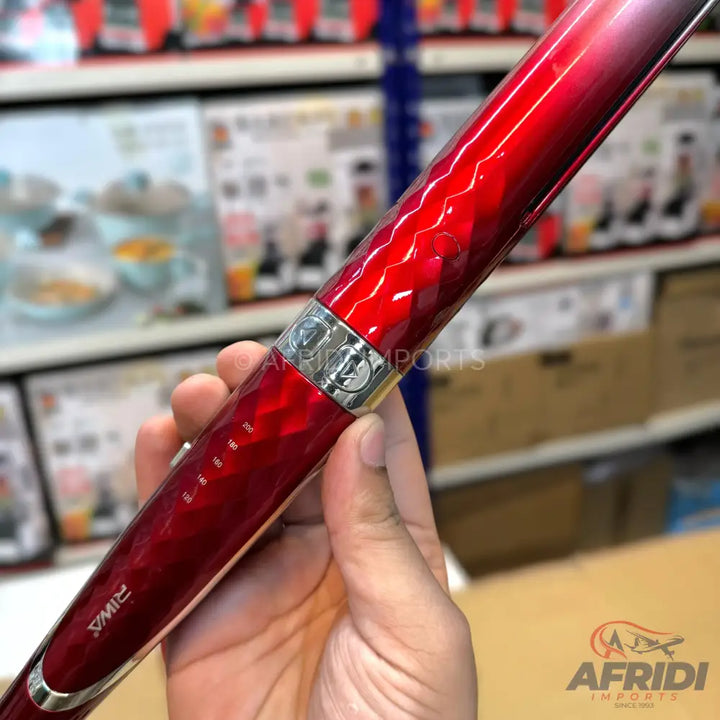 A shiny, red, faceted hair styling tool.