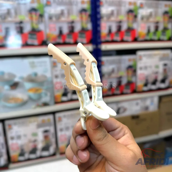 A pair of beige and white plastic hair clips with a claw design.