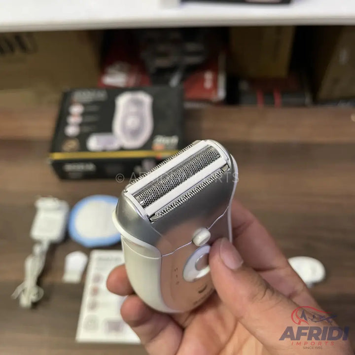 A white and silver electric shaver with a dual-foil head held in a hand.