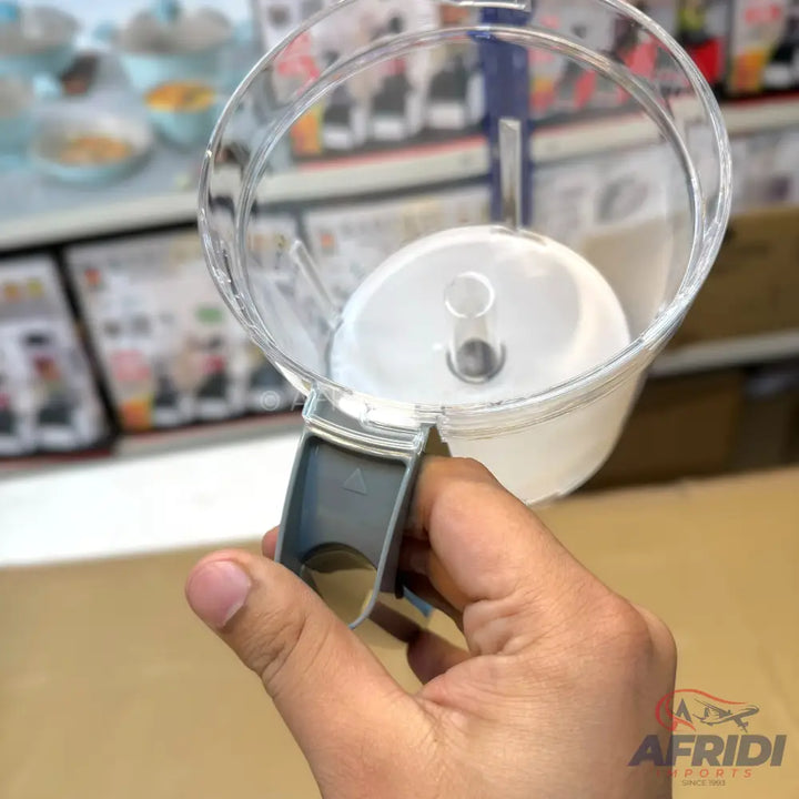 A clear plastic food processor bowl with a gray handle.