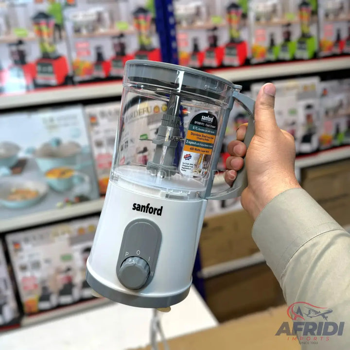 A compact white and clear plastic food processor with a gray handle, control knob, and a detachable blade assembly.