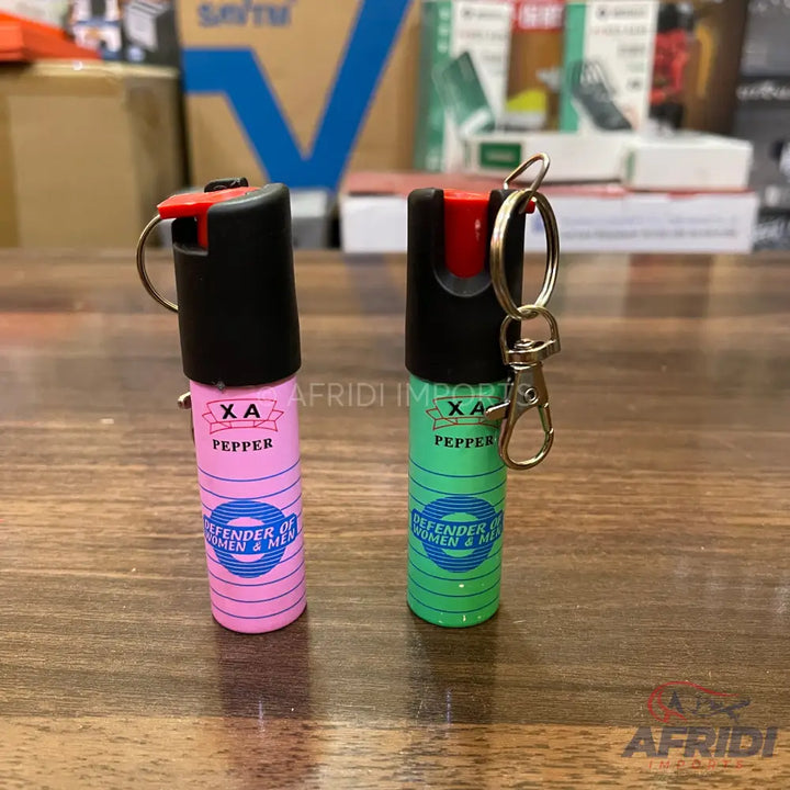 Two portable self-defense pepper spray keychains in pink and green.