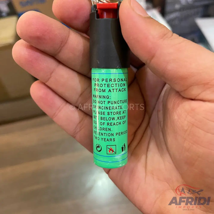 A compact, green and black canister of personal protection spray, designed for self-defense.