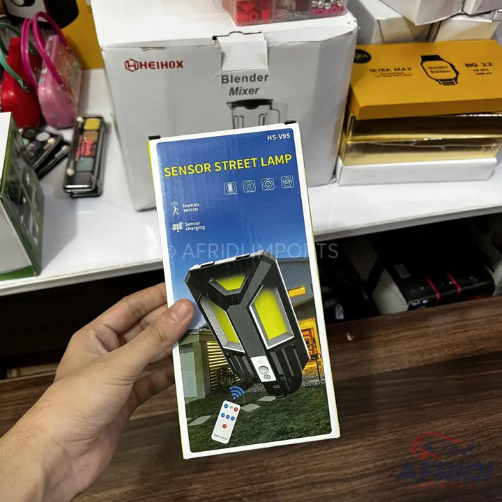 A rectangular white box containing a sensor street lamp with a remote control.