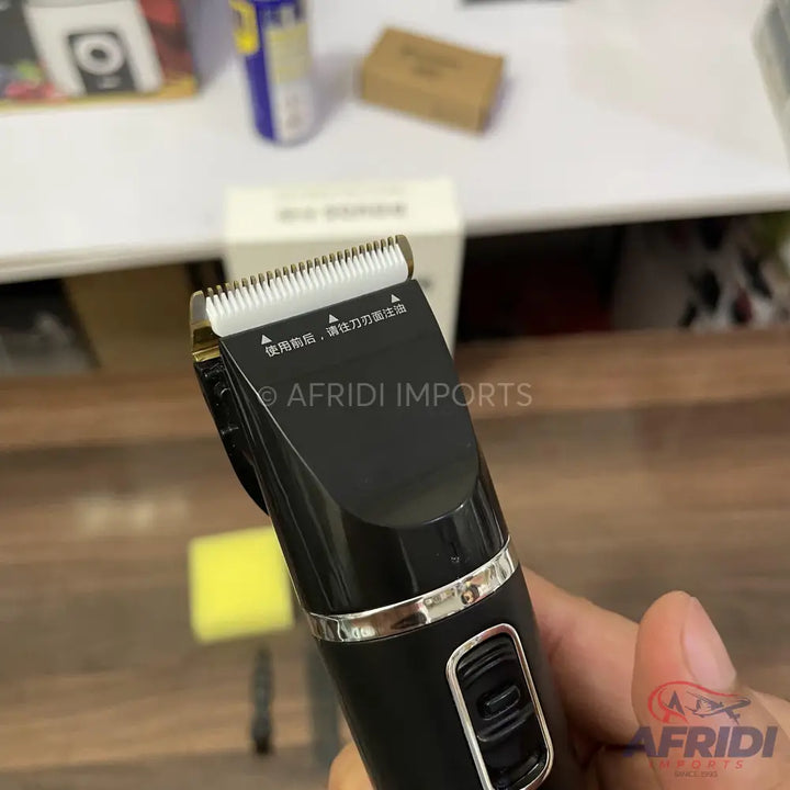 Black electric hair clipper with a silver band and white ceramic blade.