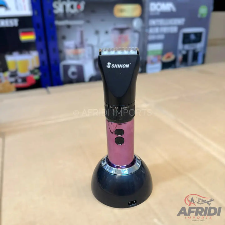 Pink and black cordless electric hair clipper with a charging stand.