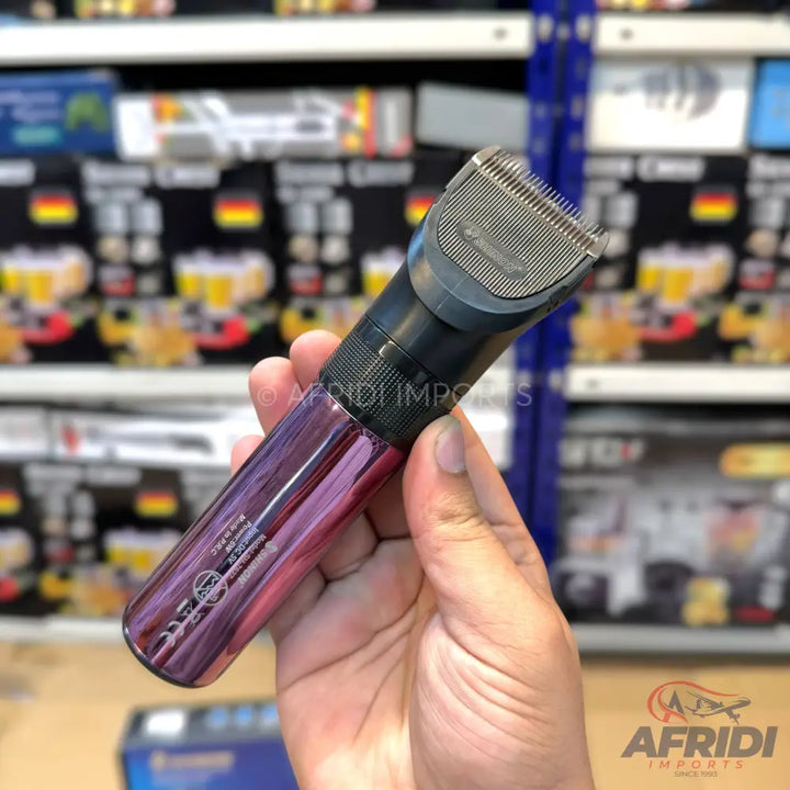 A purple and black electric hair clipper held in a hand.