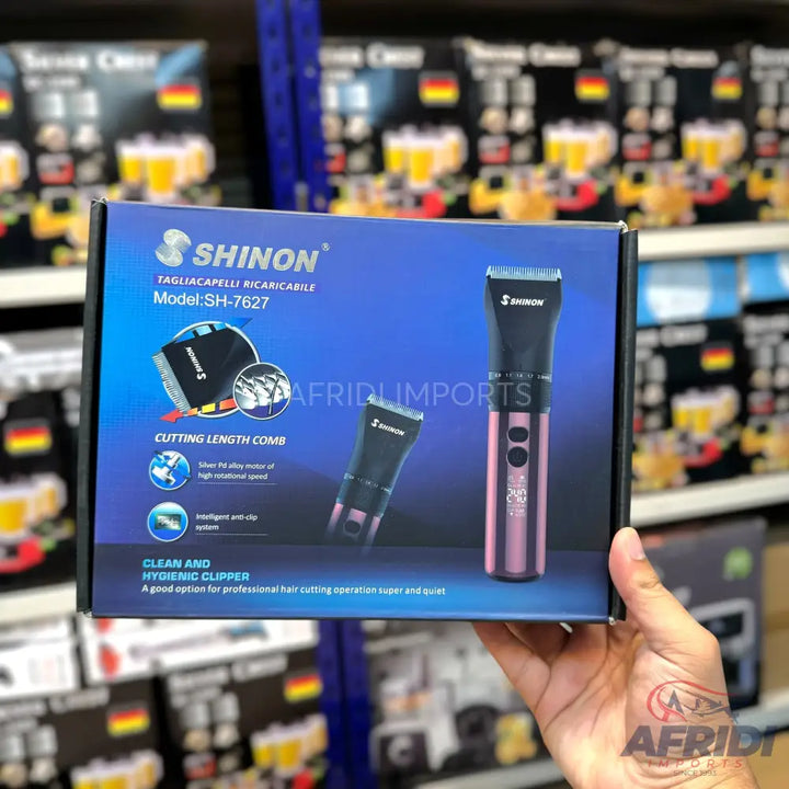 A ’SHINON’ branded rechargeable hair clipper, model SH-7627, with a cutting length comb, featuring a high-rotation speed motor and intelligent anti-clip system, designed for clean and hygienic professional hair cutting.