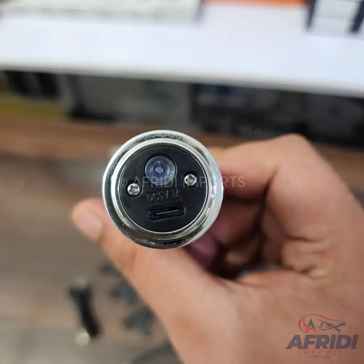 A silver-colored car charger with a USB port and an LED indicator.