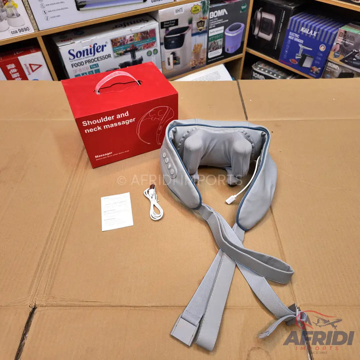 Red boxed shoulder and neck massager with an accompanying gray, U-shaped massager unit and a white charging cable.