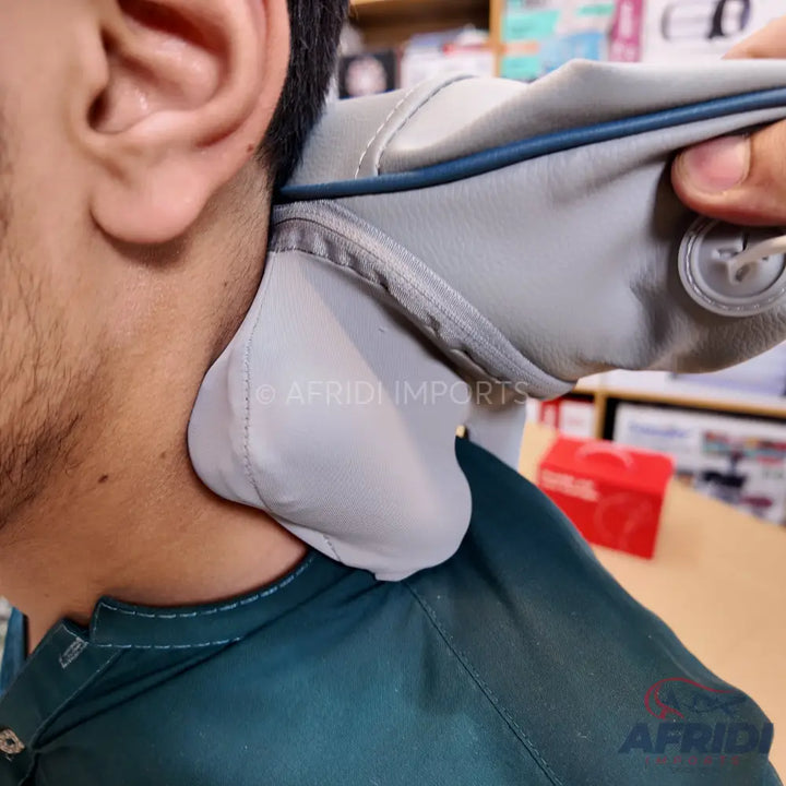 Gray neck massager with blue trim being used on a person’s neck.