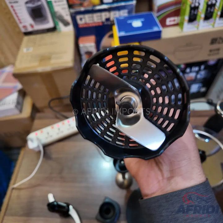 A hand blender attachment with a two-pronged blade inside a black, perforated bell.