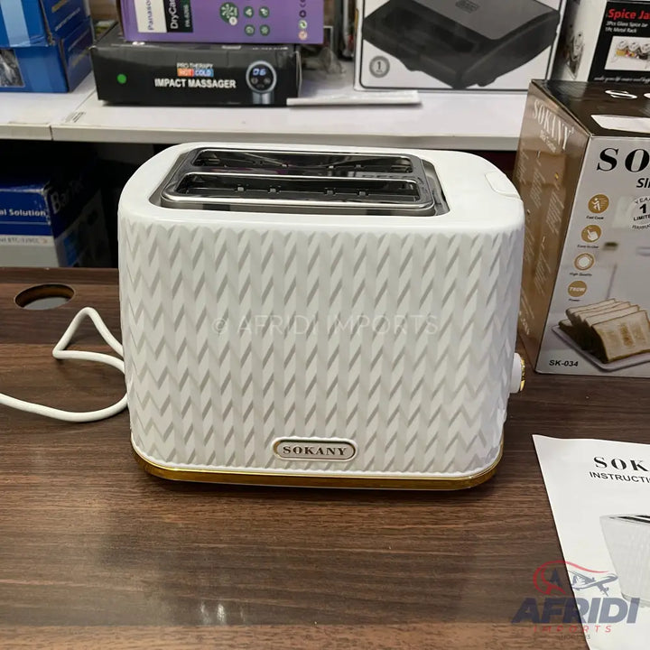 White two-slice toaster with a textured pattern and gold trim.