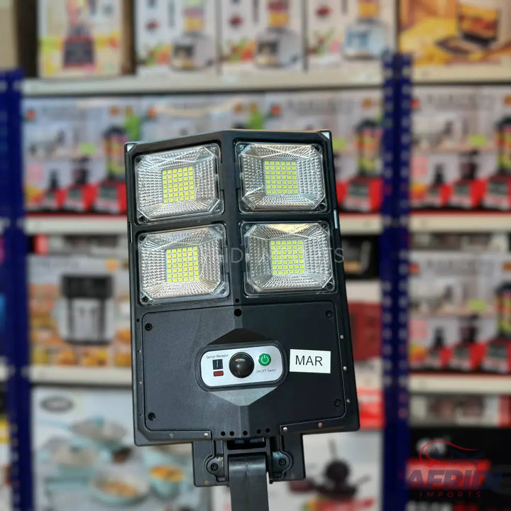 Black solar-powered LED street light with four bright panels and a control unit.