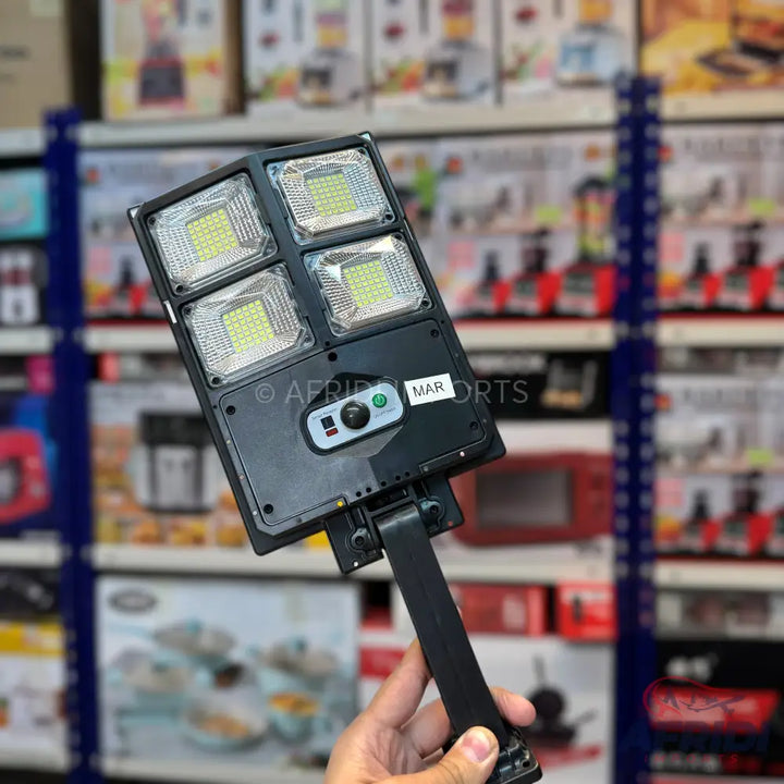 Black solar-powered LED street light with four rectangular light panels and an adjustable mounting arm.