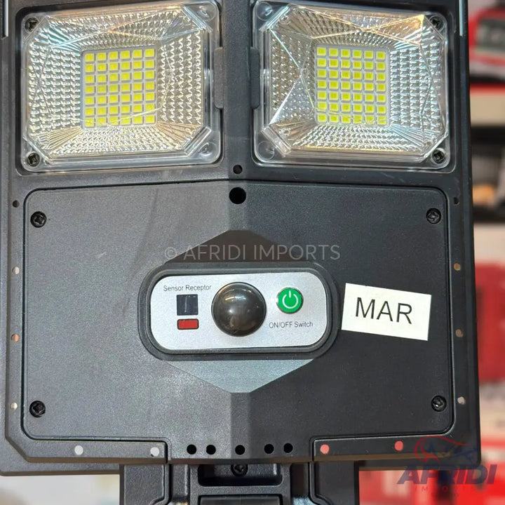 A black solar-powered LED floodlight with motion sensor and power switch.
