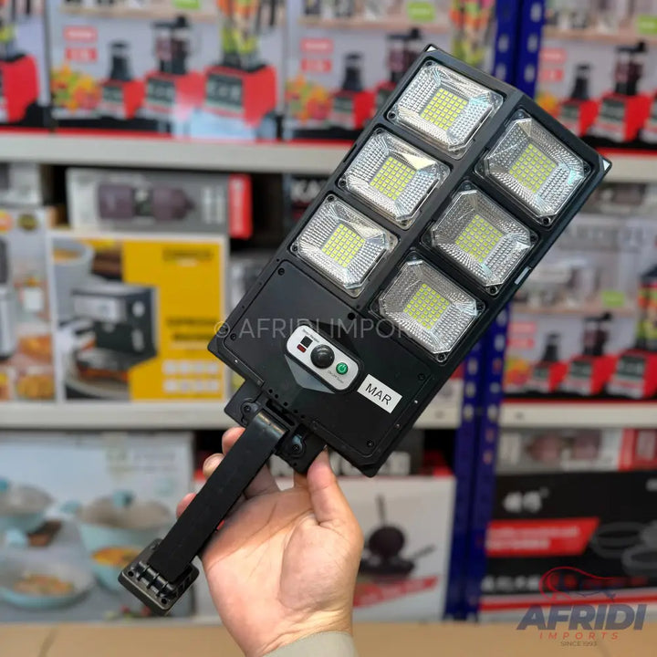 Black solar-powered LED street light with six rectangular light panels and an adjustable mounting bracket.
