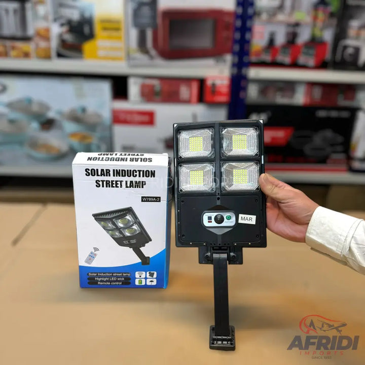 A solar induction street lamp with four LED panels and a remote control.