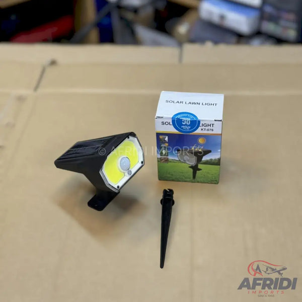 Black solar-powered lawn light with a white LED panel and a ground stake.