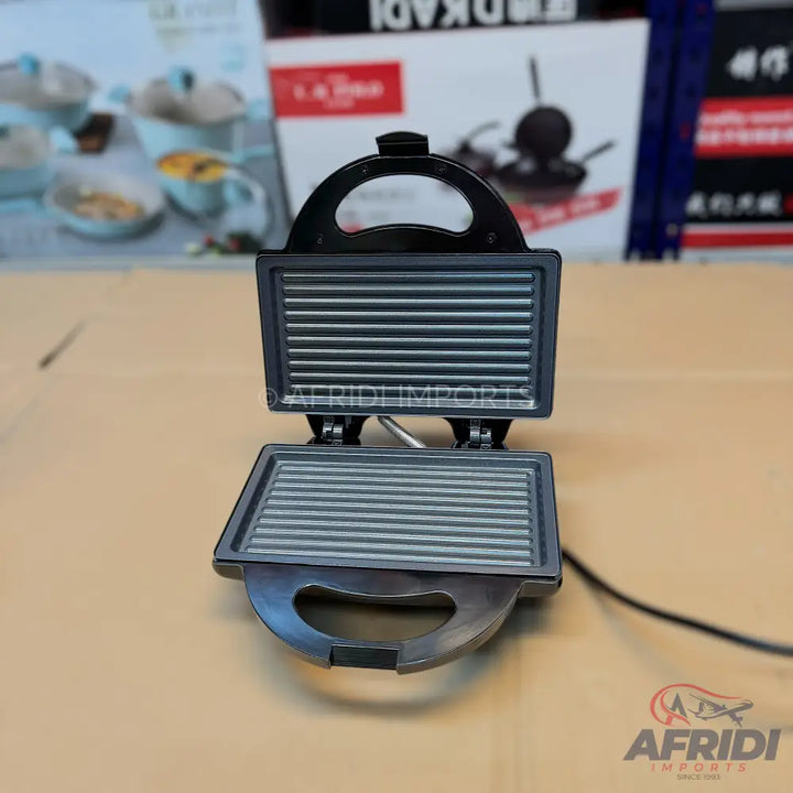 An open black electric sandwich maker with ridged plates.