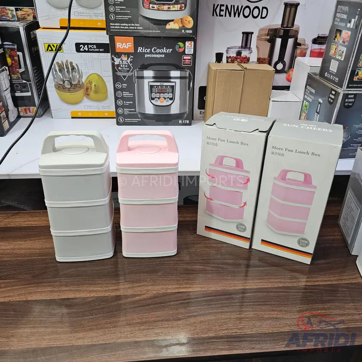 Two three-tiered stackable lunch boxes with carrying handles, one in light grey and one in pink.