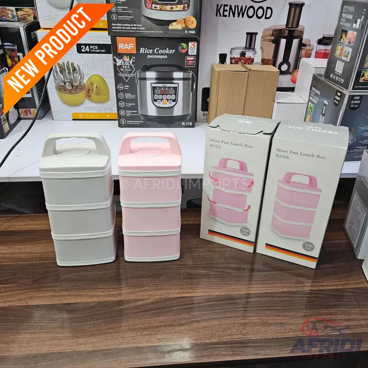 Two three-tiered stackable lunch boxes with carrying handles, one in light grey and one in pink.