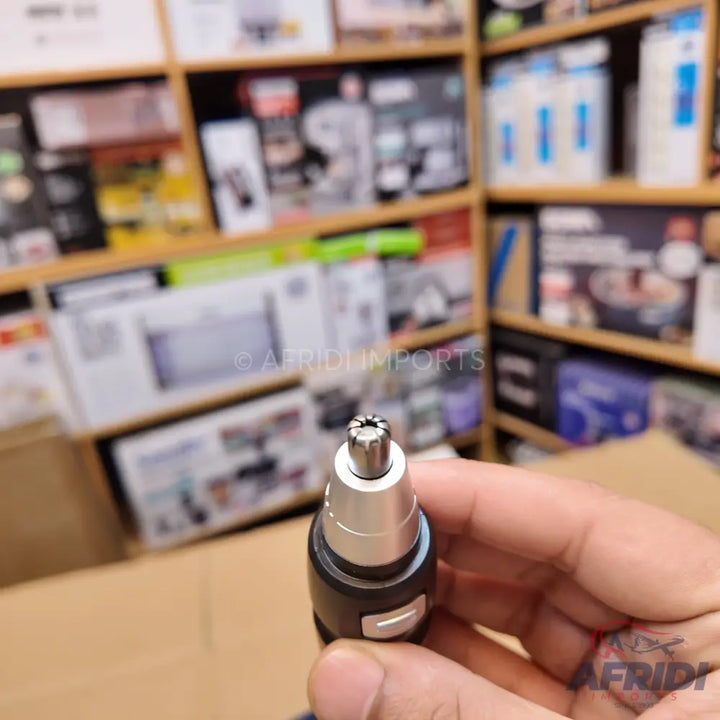 A handheld nose and ear hair trimmer with a cylindrical cutting head.
