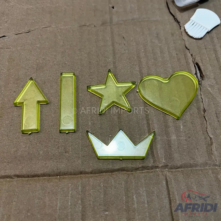 Five transparent yellow plastic shapes: an arrow, a rectangle, a star, a heart, and a crown.