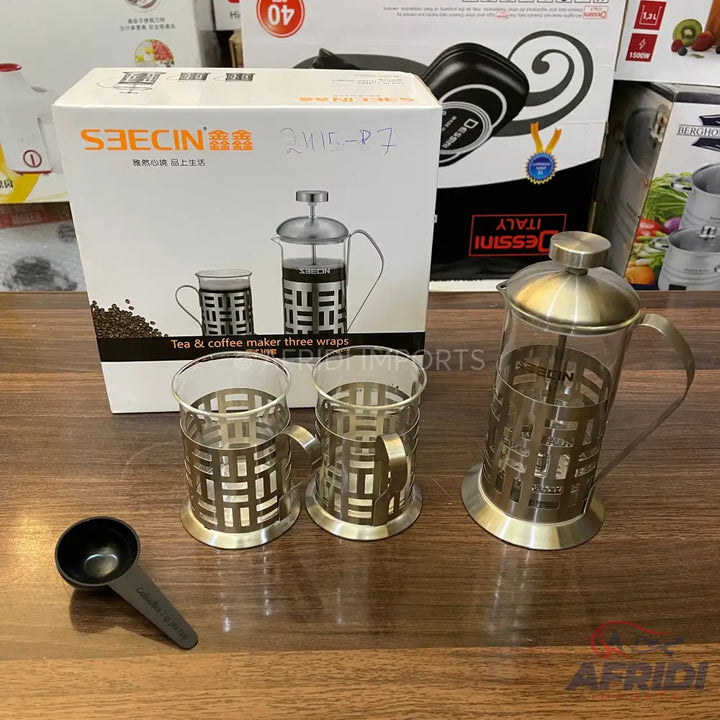 A set of a metal and glass French press coffee maker with two matching mugs and a scoop.