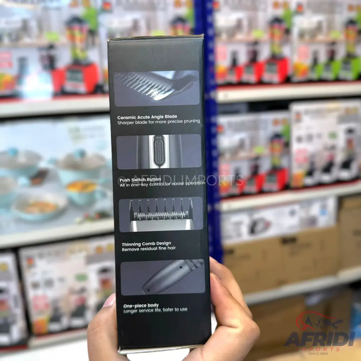 Black product box for hair clippers, highlighting features like a ceramic acute angle blade, push switch button, thinning comb design, and one-piece body.