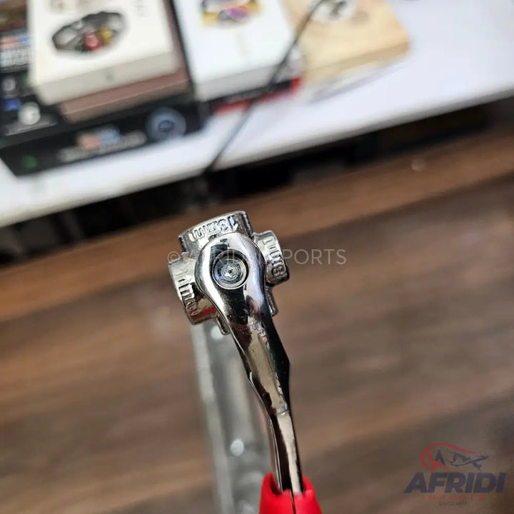 A shiny, chrome-plated ratchet wrench with a red handle.