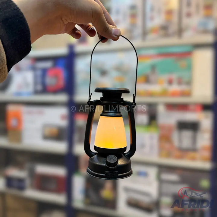 Black portable LED lantern with a warm yellow glow.