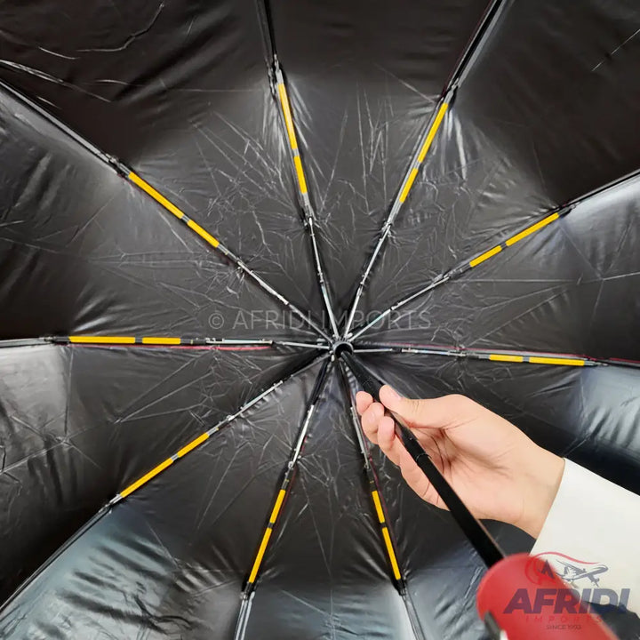 An open black umbrella with yellow-accented ribs and a red handle.