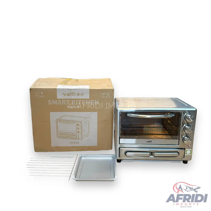 A silver countertop toaster oven with a transparent door, three control knobs, and a pull-out crumb tray, accompanied by its original cardboard packaging, a baking tray, and a wire rack.