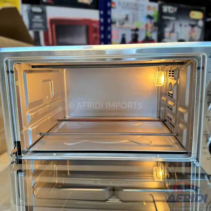 An empty, illuminated stainless steel toaster oven with multiple racks.